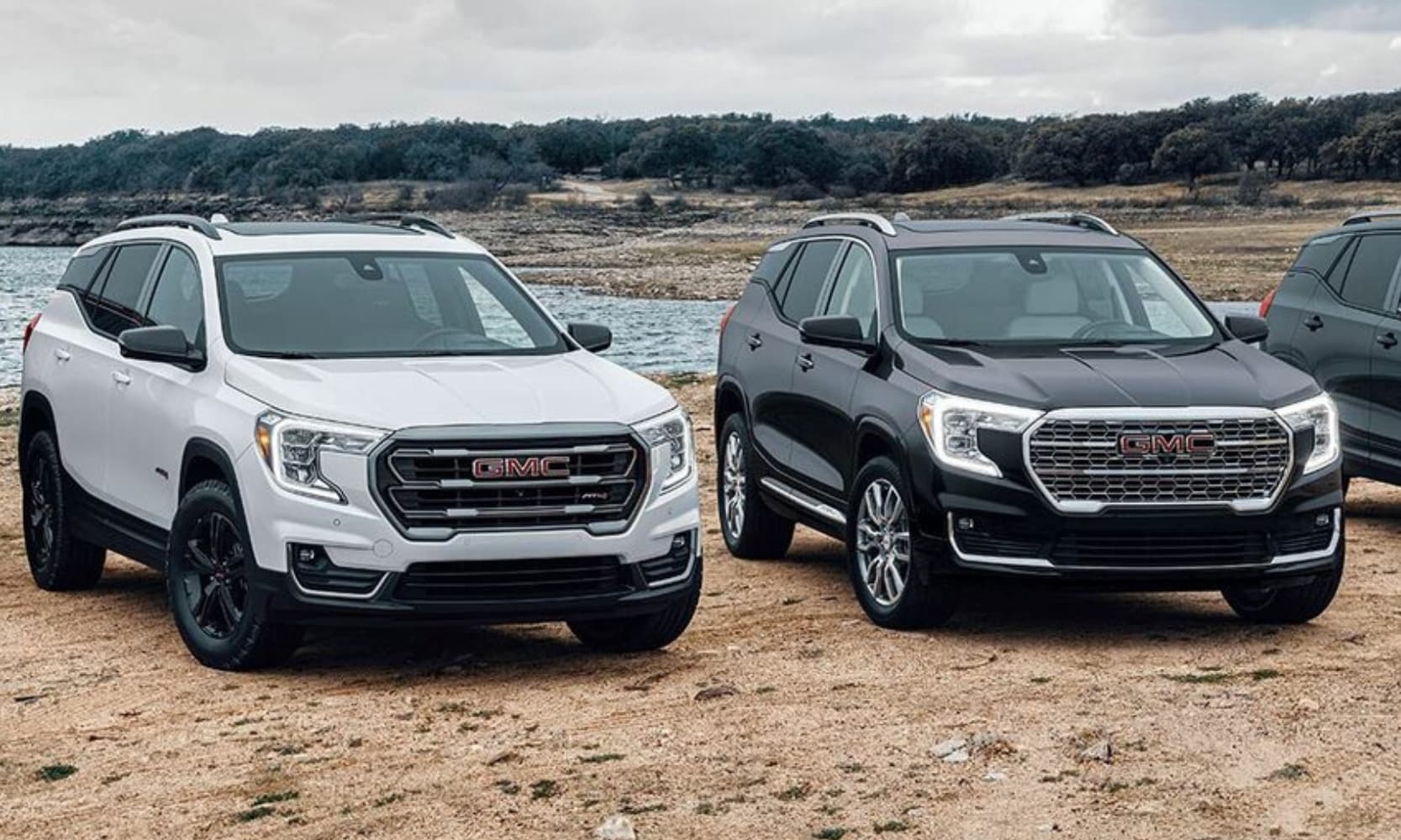 a 2023 GMC Terrain AT4 parked next to a 2023 GMC Terrain Denali on the edge of a cliff