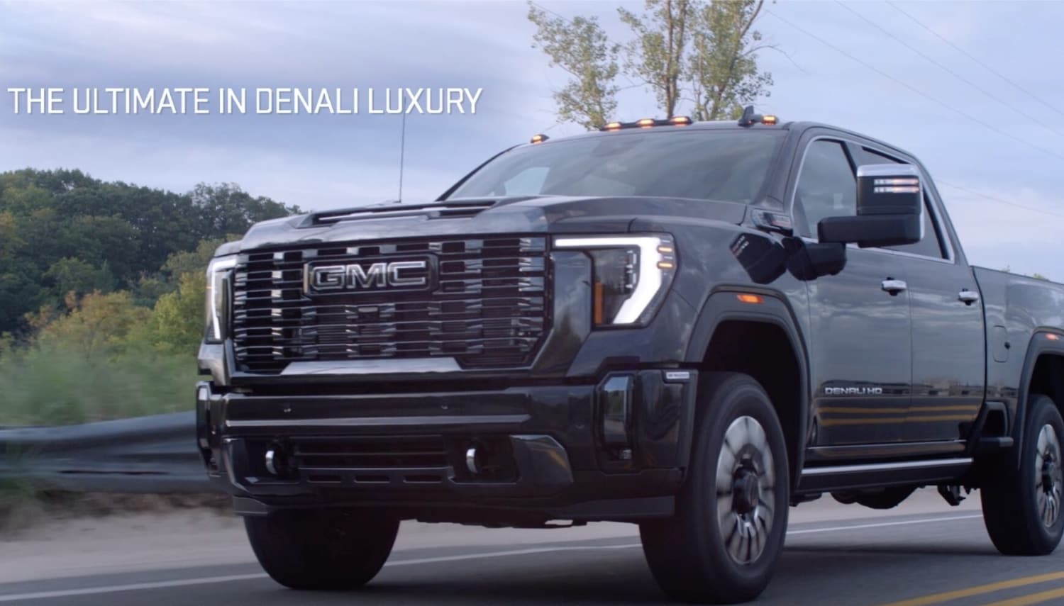 New 2024 GMC Sierra 2500 Heavy Duty Truck Comparison - Octane GMC of Santa Fe.jpg a 2024 GMC Sierra HD Denali Ultimate truck driving down the road in style with the text 'the ultimate in Denali luxury' overlay in the corner of the image