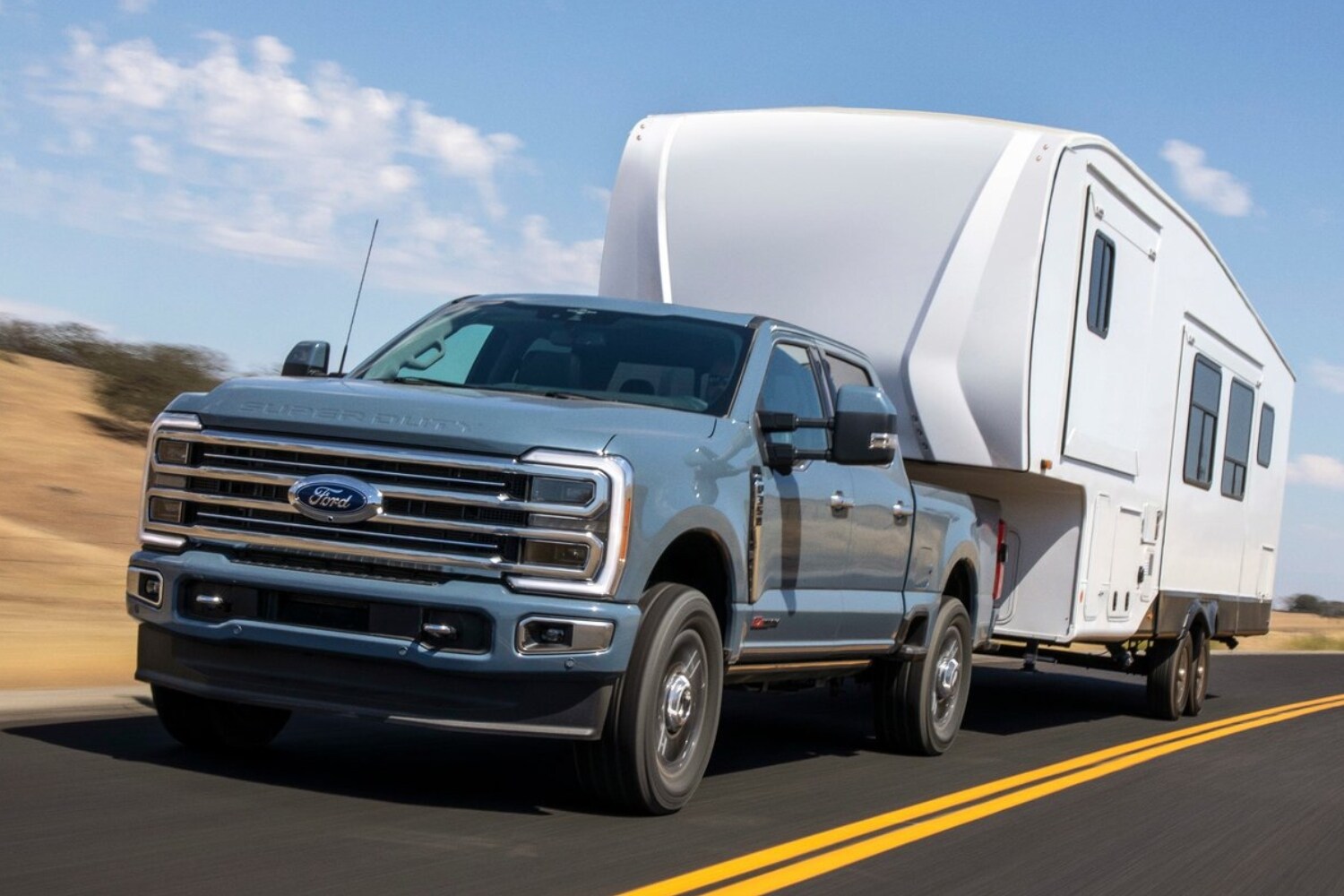 New 2023 Ford Super Duty Towing Capacity Comparison - Octane GMC of Santa Fe.jpg Image of a 2023 Ford Super Duty truck towing a large camper down a highway