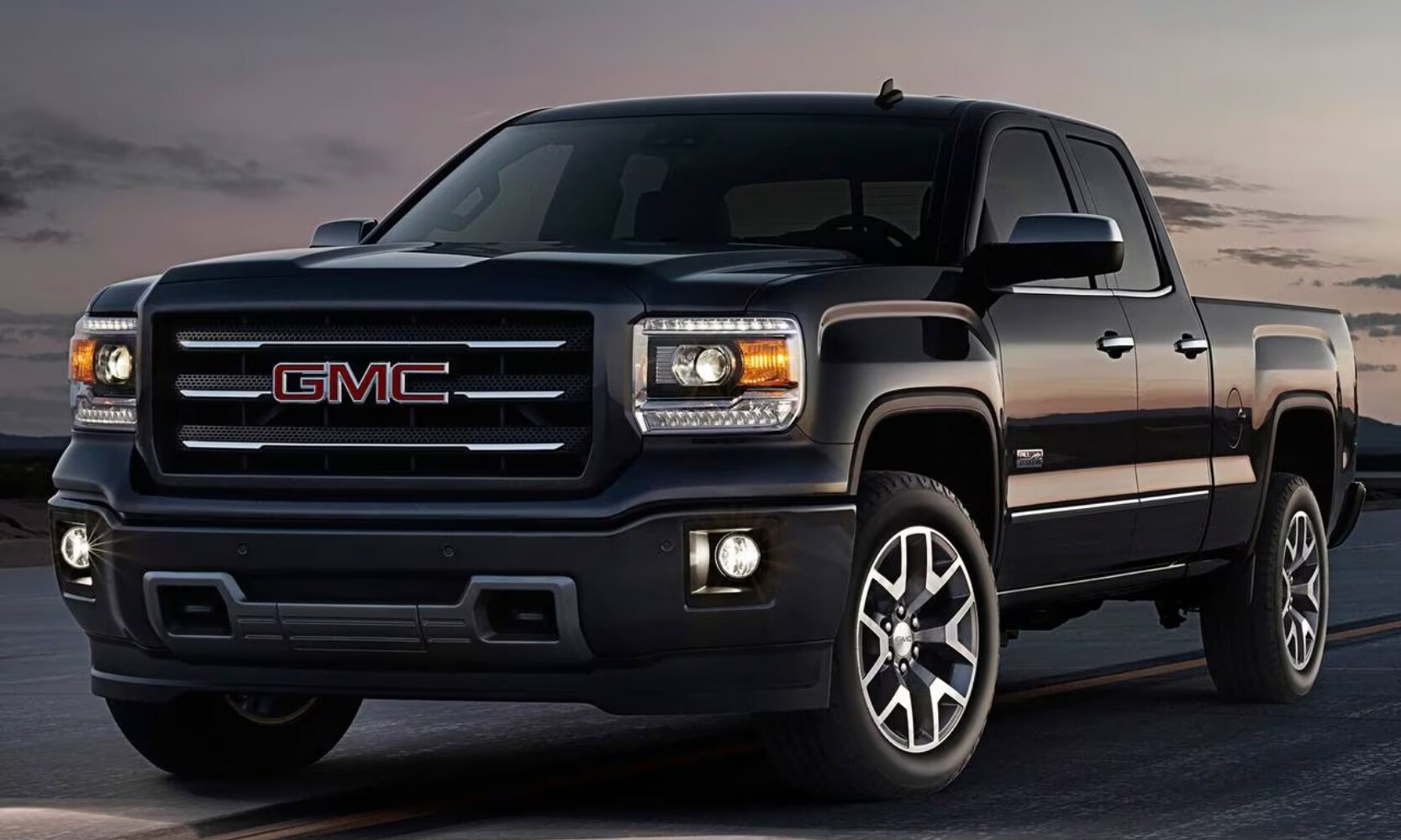 photo of a black 2016 GMC Sierra 2600 HD SLT Truck driving on a highway during sunset