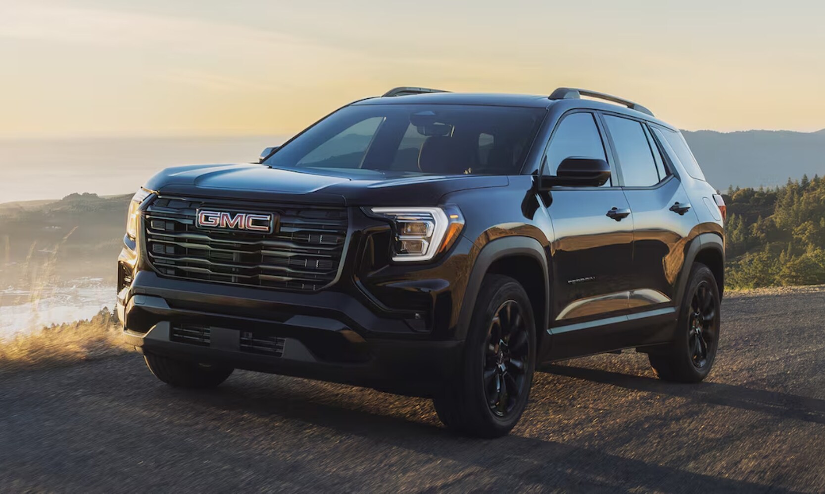 2026%20GMC%20Terrain%20Engine%20-%20Octane%20GMC%20of%20Santa%20Fe.jpg Exterior front side angle image of a black 2026 GMC Terrain Black Edition driving down a coastal highway