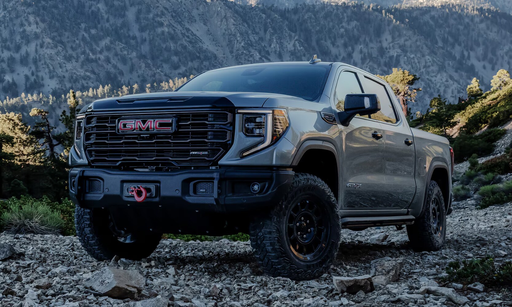 2026%20GMC%20Sierra%201500%20FAQs%20-%20Octane%20GMC%20of%20Santa%20Fe.png Exterior front angle image of a gray 2026 GMC Sierra 1500 AT4X AEV Edition parked on rocky terrain in a mountainous setting