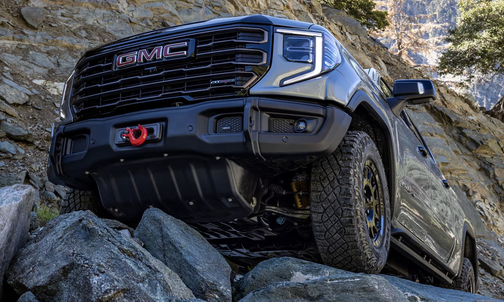 2025%20GMC%20Sierra%201500%20vs.%202025%20RAM%201500%20-%202025%20GMC%20Sierra%201500%20Off-Road%20Comparison-%20Octane%20GMC%20of%20Santa%20Fe.jpg Closeup front exterior image of a gray 2025 GMC Sierra 1500 AT4 parked on a rocky hill in a mountainous landscape