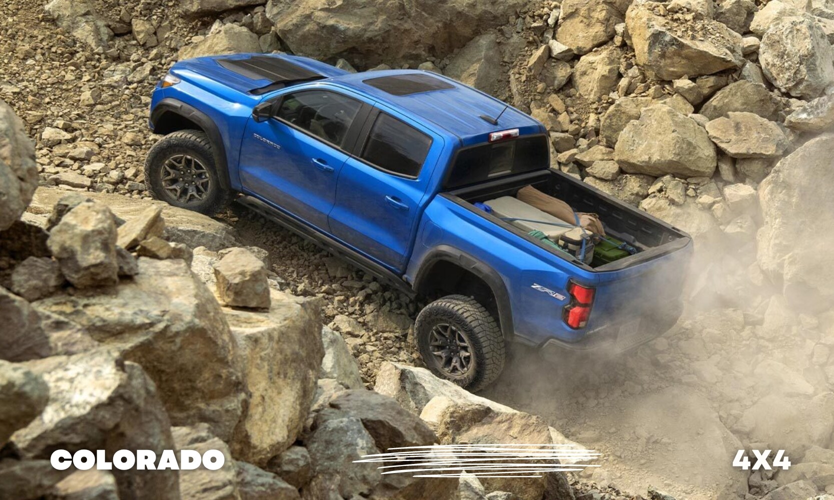 Best%20Used%20Chevy%20Colorado%204x4%20Trucks%20-%20Octane%20GMC%20of%20Santa%20Fe.jpg an off-road 4x4 Chevy Colorado truck going up a rocky path with camping gear loaded in the truck bed