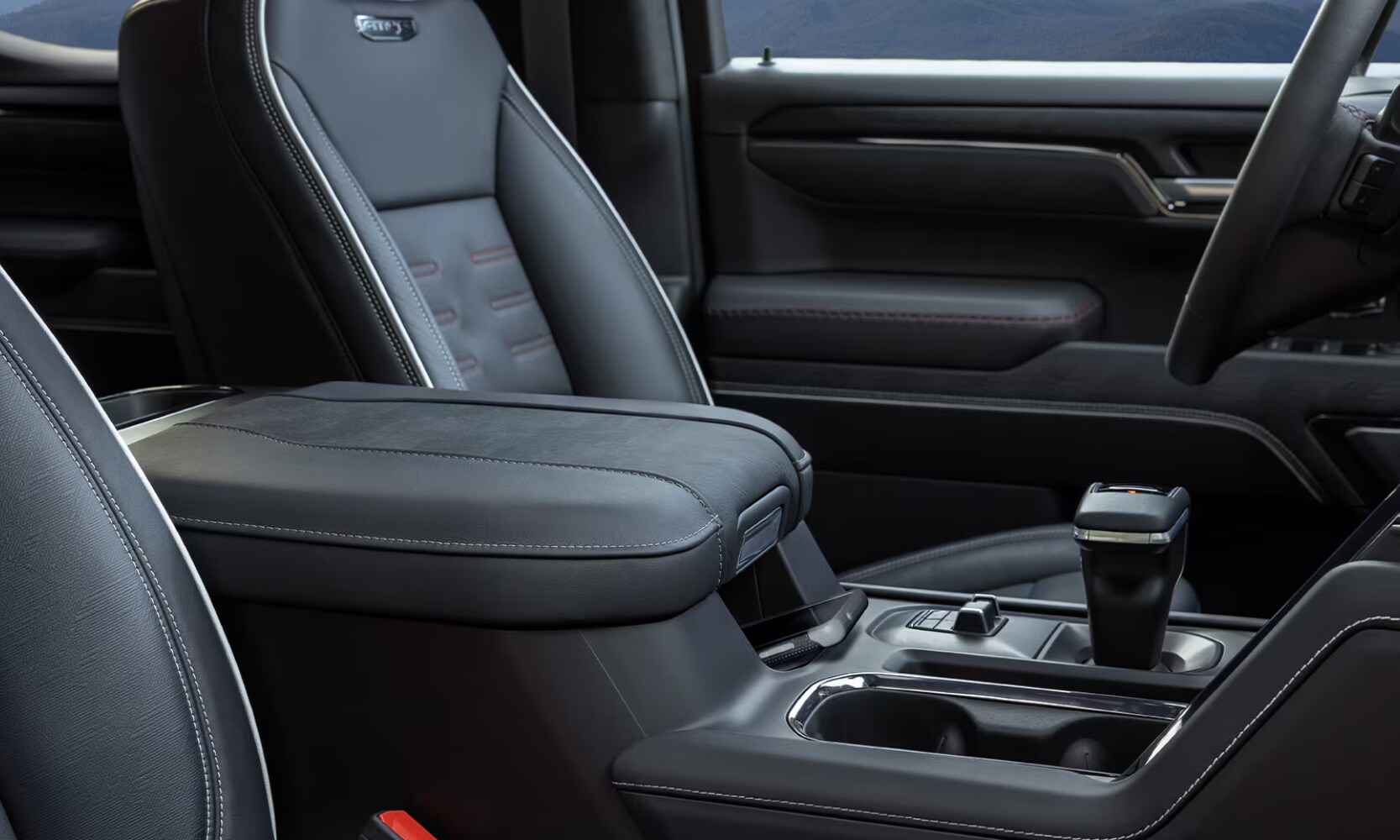 2026%20GMC%20Sierra%201500%20Interior%20Cargo%20-%20Octane%20GMC%20of%20Santa%20Fe.png Closeup image of the 2026 GMC Sierra 1500 black leather front seat area, center console, and gear knob