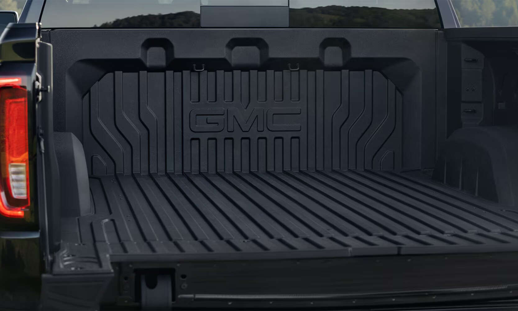 2026%20GMC%20Sierra%201500%20Exterior%20Design%20-%20Octane%20GMC%20of%20Santa%20Fe.png Closeup image of the 2026 GMC Sierra 1500's black CarbonPro composite bed with it opened