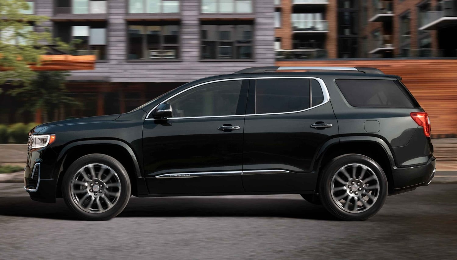 Exterior view of a 2023 GMC Acadia midsize SUV driving down a city street