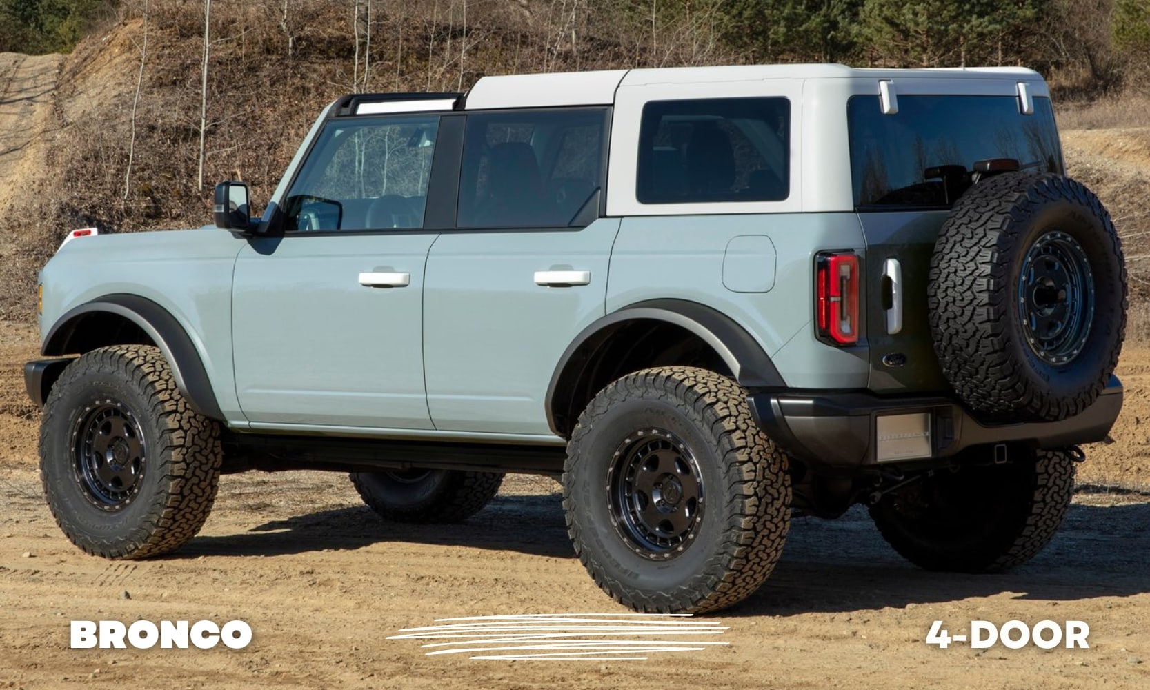 Rear driver side angle of a blue 4 door Ford Bronco with a white hardtop roof parked on a dirt road