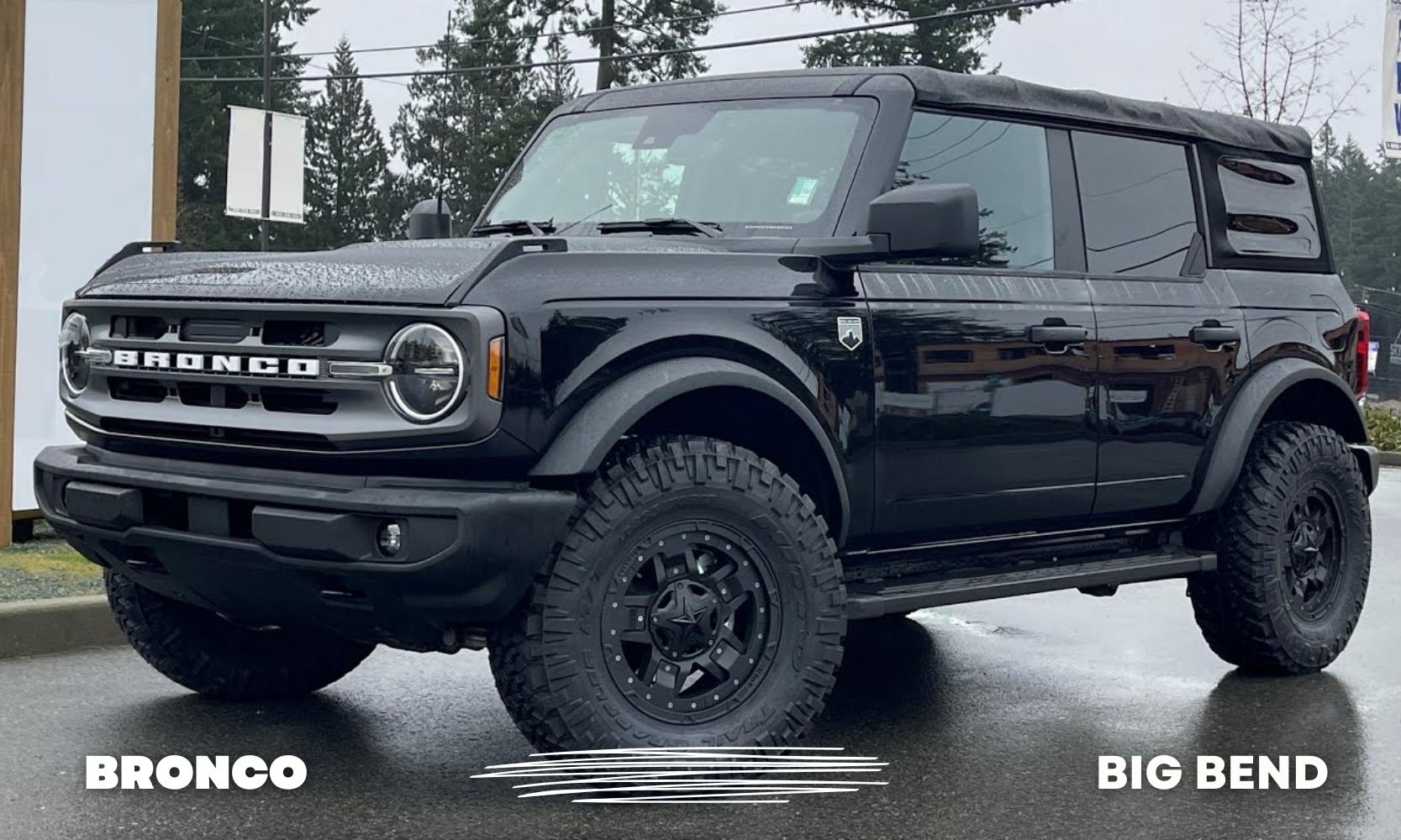 Driver side angle of a black Ford Bronco Big Bend model parked with rain drops rolling off the hood and roof