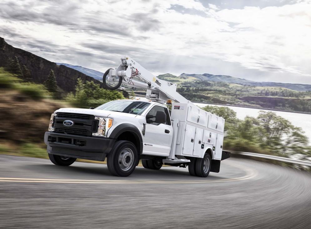 2017_FRD_F550XLWhiteChassisCabBucketTruck.png white Ford F-550 chassis cab truck coming around a corner