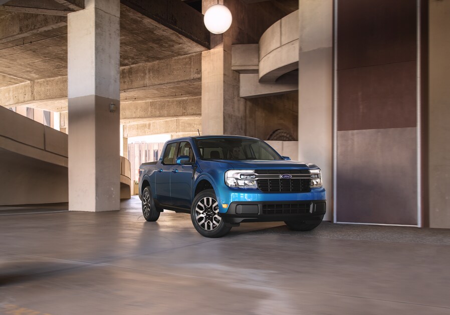 2022-Ford-Maverick-XL-SuperCrew-Truck-L02.png blue Ford Maverick truck parked in a modern cement building with columns and stairs nearby
