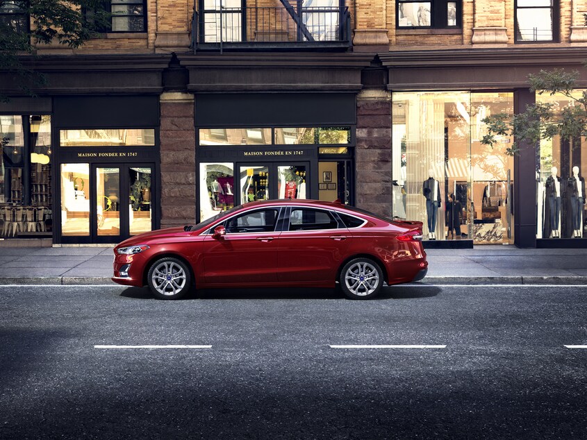 2020-Ford-Fusion-SEL-Sedan-L01.png dark red Ford Fusion parked in front of a downtown retail area