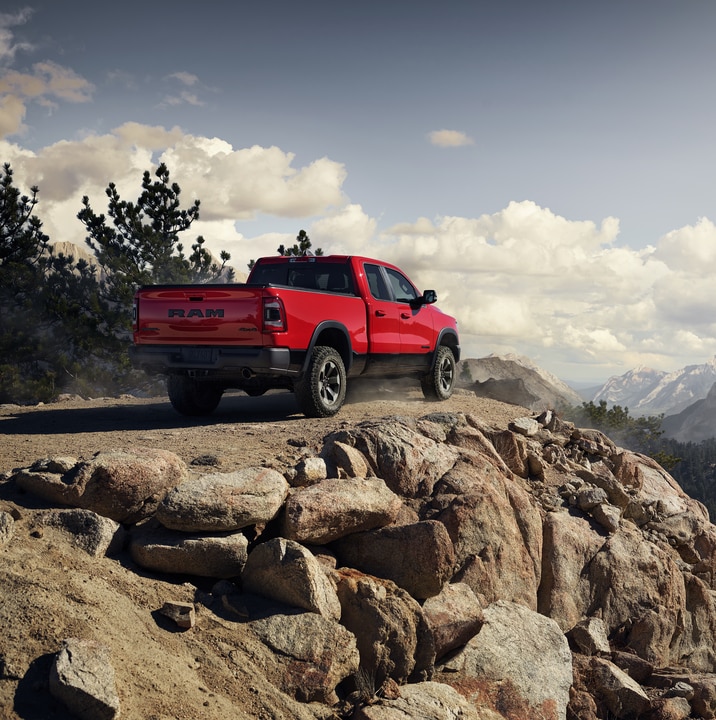 2019-RAM-1500-Limited-Quad Cab-Truck-L04.png bright Red Ram 1500 truck parked on a high ridge, overlooking a forested valley