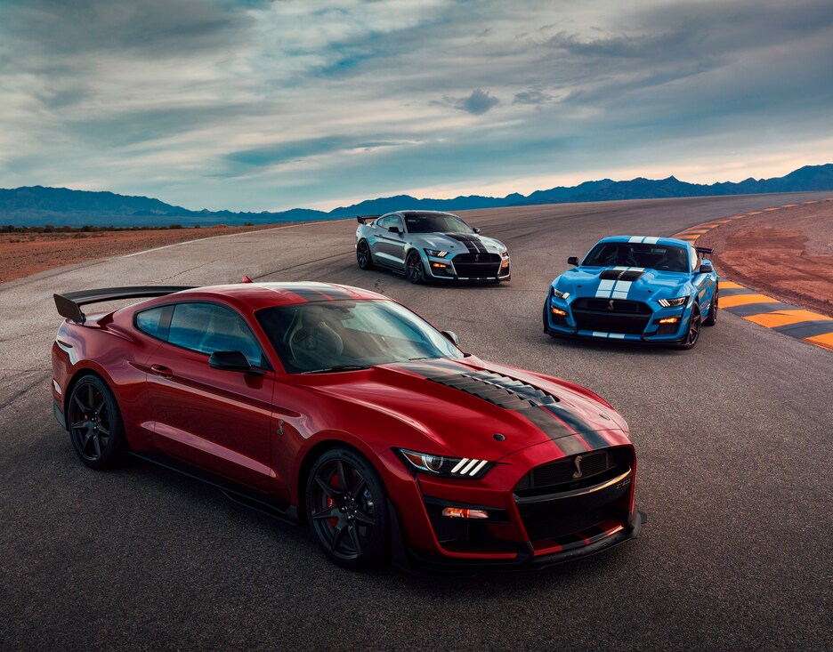 2023-Ford-Mustang-Lineup-01.png red, blue, and white Ford Mustang lineup parked on a race track