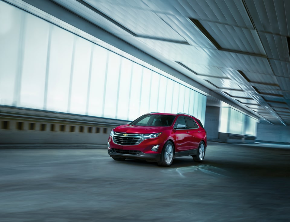 2018-Chevrolet-Equinox-Premier-SUV-L01.png cherry red Chevy Equinox SUV driving through an empty indoor track