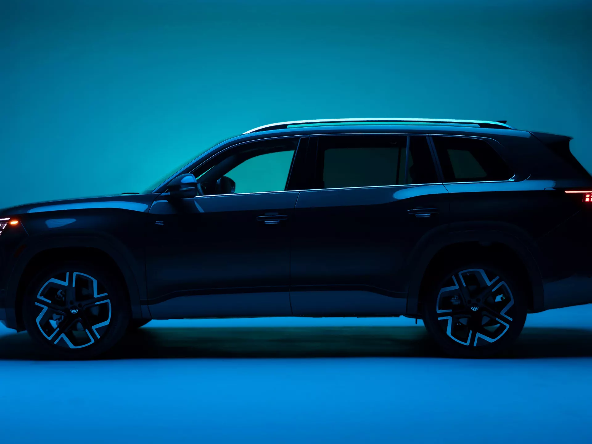 Side profile of the all-new 2027 Volkswagen Atlas in Sacramento Green Metallic in a dramatically lit studio