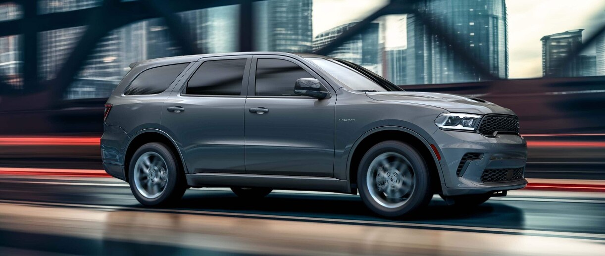 A gray Dodge Durango driving over a bridge in a city. A gray Dodge Durango driving over a bridge in a city.