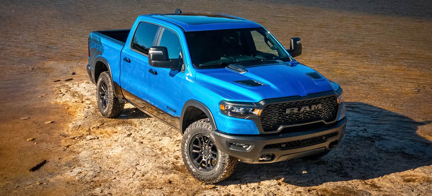 A blue 2026 RAM 1500 in a desert. A blue 2026 RAM 1500 in a desert.