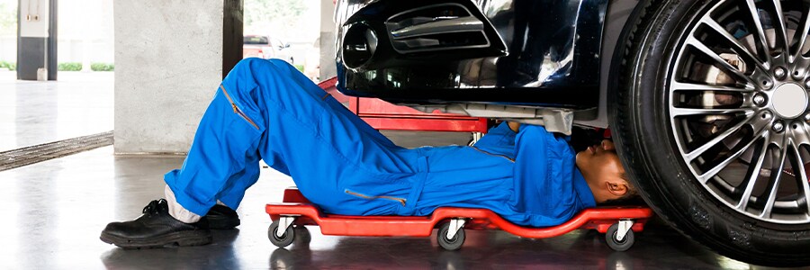 Service Technician under a car working on it