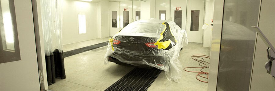 Black Toyota Camry Covered in Plastic in a Repair Bay