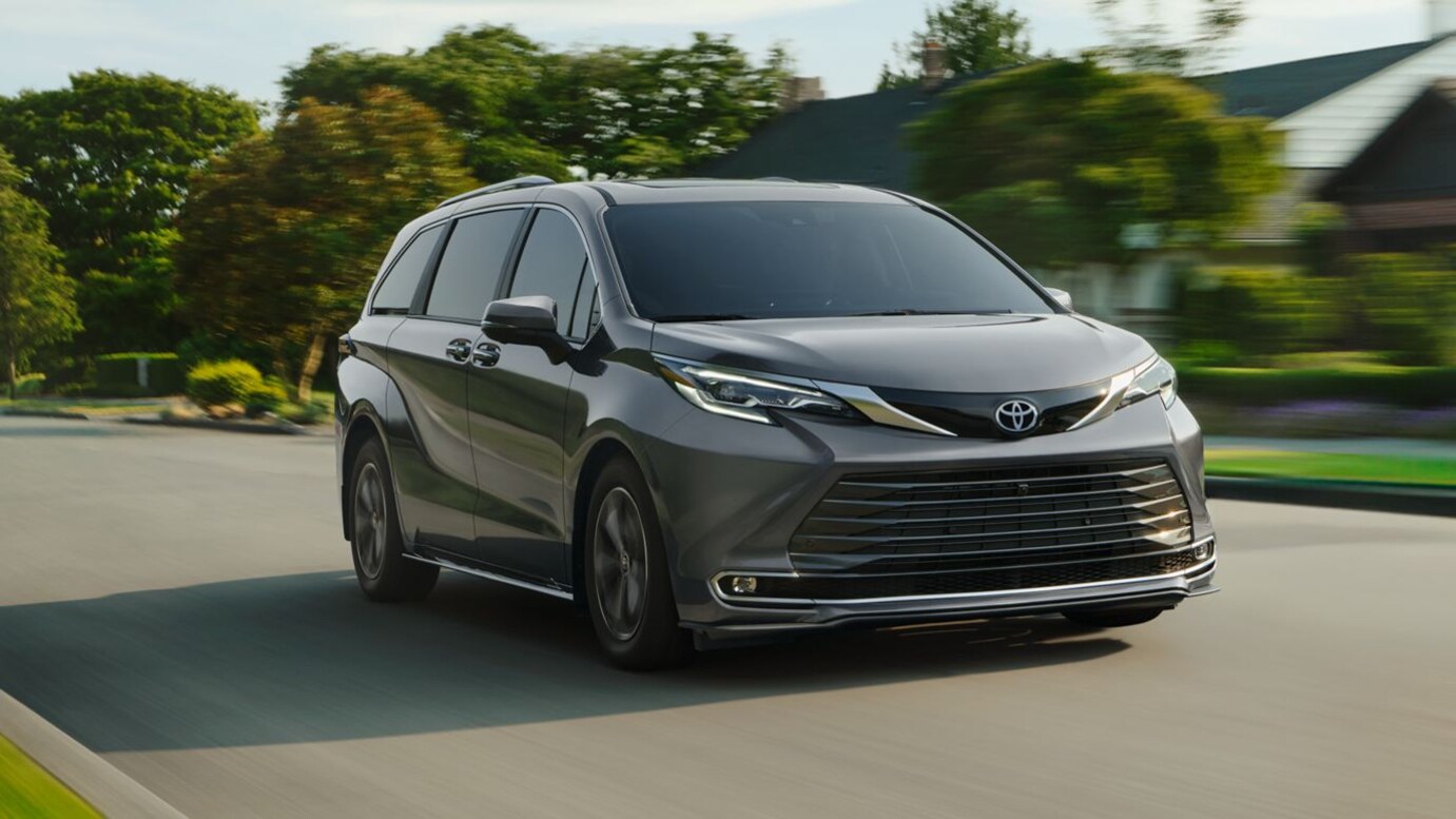 A gray Toyota Sienna driving through a suburban neighborhood.