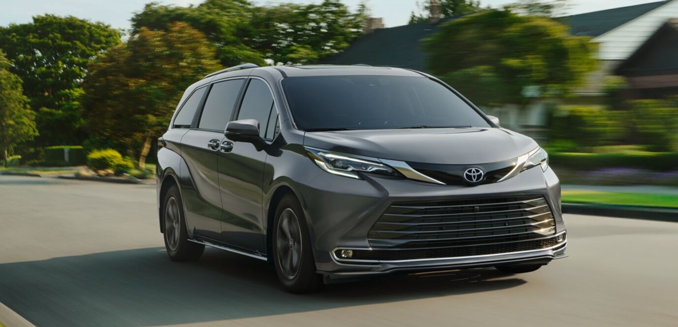 A gray Toyota Sienna driving through a suburban neighborhood.
