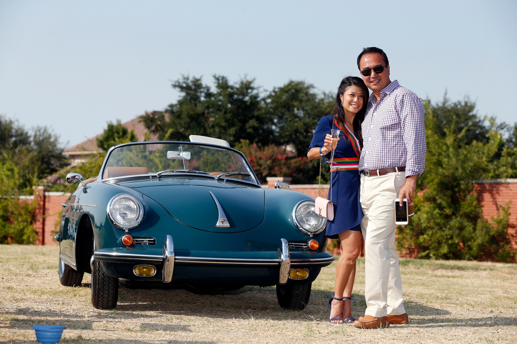 A classic Euro car poses with a smiling couple