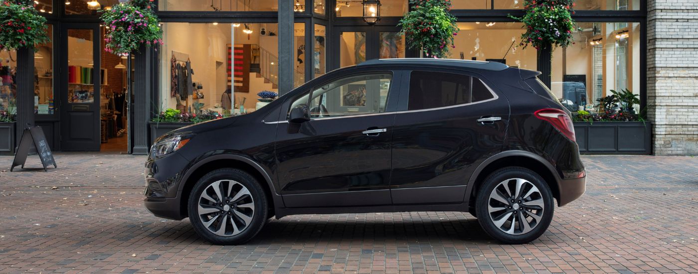 Side of a black 2022 Buick Encore driving in a city.