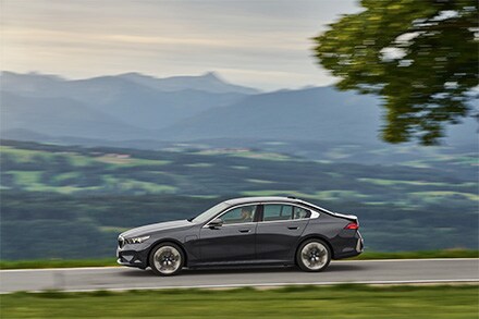 BMW 5 Series sedan in motion on a winding road, capturing its blend of dynamic performance and refined luxury design.