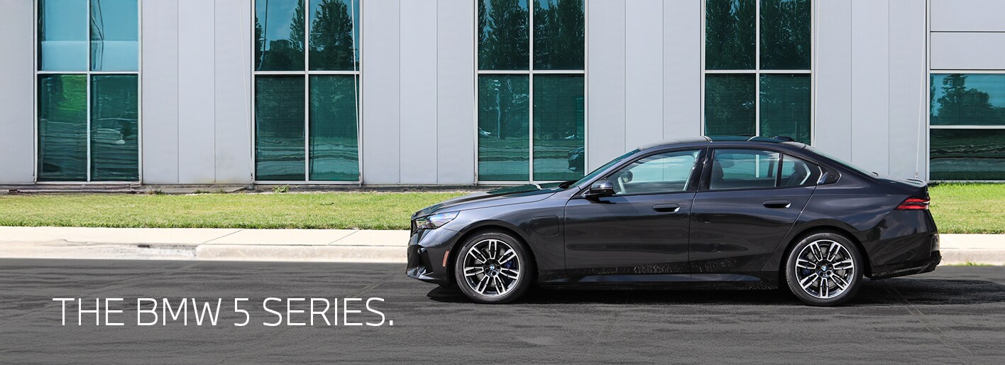 The all-new 2026 BMW 5 Series sedan in motion on a scenic road, highlighting its bold design and advanced features-available now at Patrick BMW.