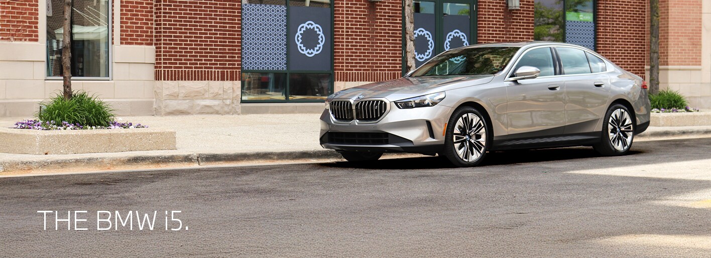 BMW i5 electric sedan showcased on a sleek modern road with city skyline in the background, highlighting its futuristic design and luxury features.