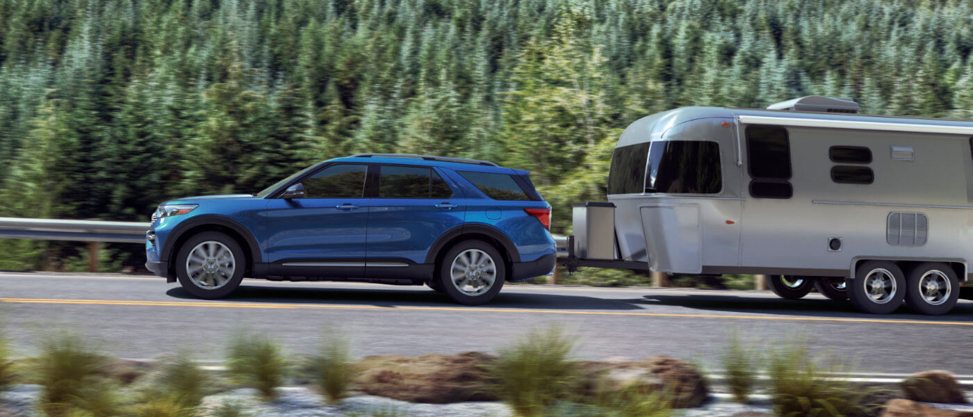 Blue 2020 Ford Exxplorer towing trailer down the road