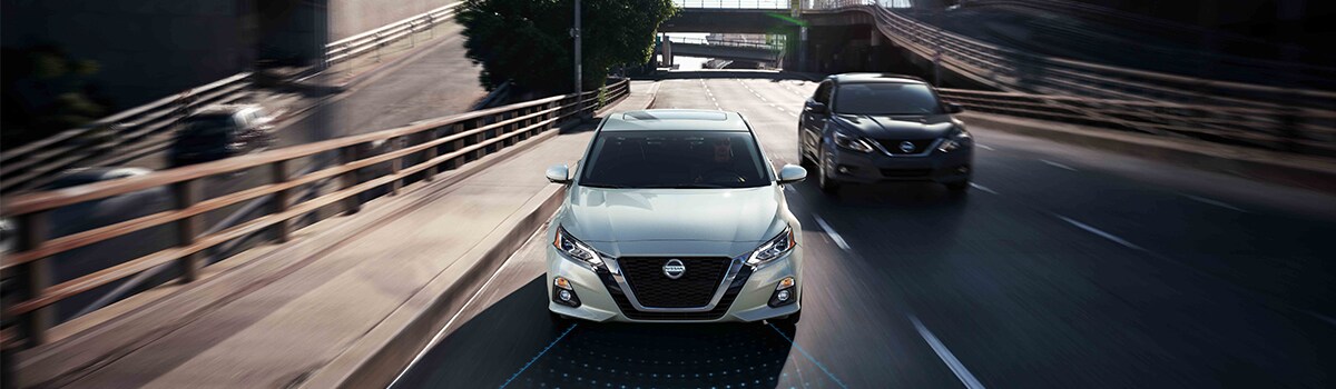 White and Black Nissan Altimas Driving