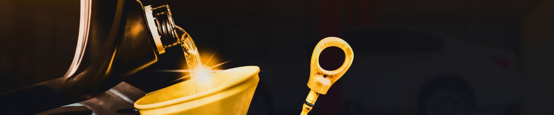 Close-up of motor oil pouring into engine funnel with dipstick, symbolizing car oil change service