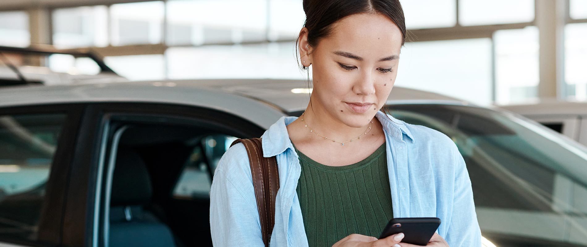 Why Buy from Peoria Toyota Young woman reviewing model information on her phone