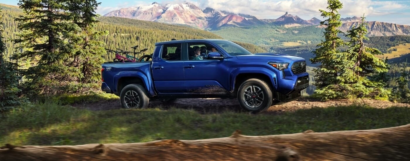 A blue 2024 Toyota Tacoma from the side.