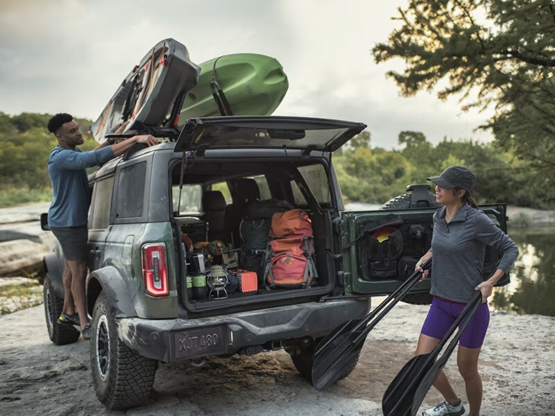 Ford Bronco Sport with the back door open and full of outdoor gear with canoes attached to the top of the SUV