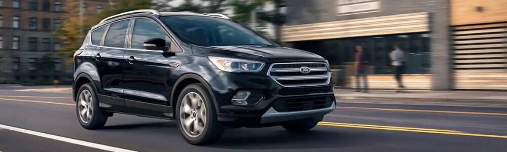 2019 Ford Escape models in Colorado Springs at Phil Long Ford Chapel Hills.png Passenger side view of a black 2019 Ford Escape driving down a city street in Colorado Springs