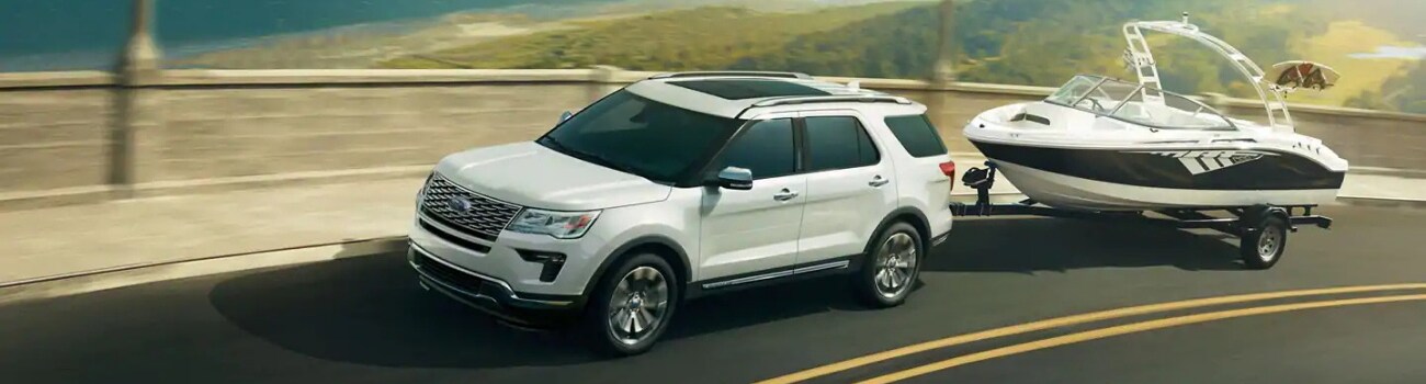 2019 Ford Explorer models in Colorado Springs at Phil Long Ford Chapel Hills.png Aerial driver side view of a white 2019 Ford Explorer in Colorado Springs towing a boat as the Ford SUV drives down the highway
