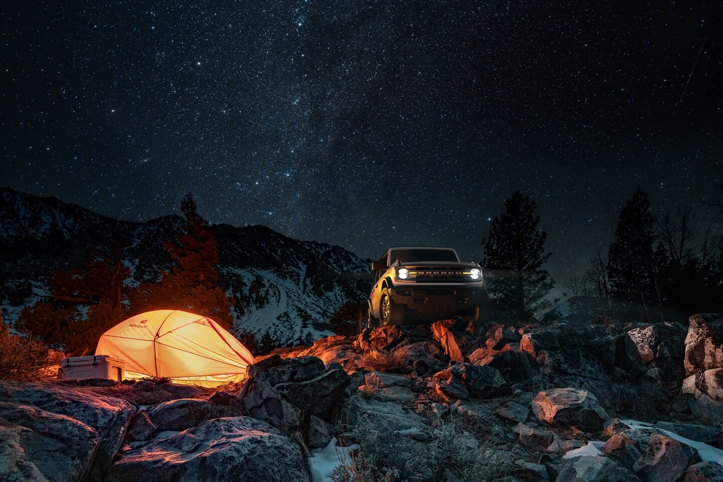 23_FRD_BRO_49891_Big_Bend.jfif A Ford Bronco parked it the wilderness with a starry sky behind it.
