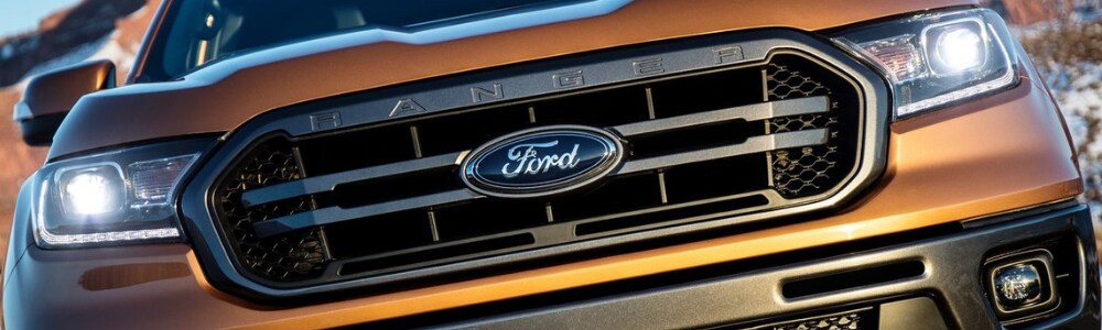 2019 Ford Ranger Truck in Colorado Springs at Phil Long Ford of Chapel Hills.png Close up view of the grill of an orange 2019 Ford Ranger truck with headlights glaring into the camera lens