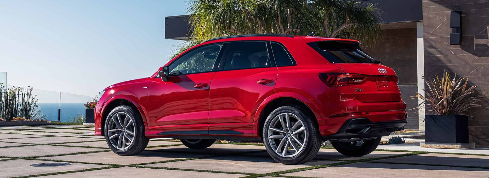 2023-audi-q3-1.PNG A view of the profile and back of a red 2023 Audi Q3