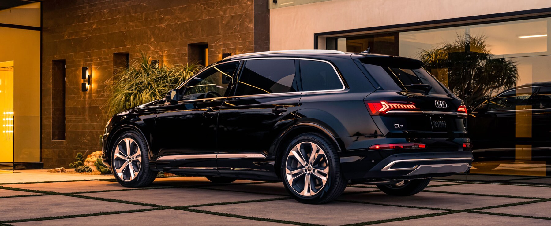 2023-audi-q7-1.PNG A black 2023 Audi Q7 parked in the driveway of a modern home