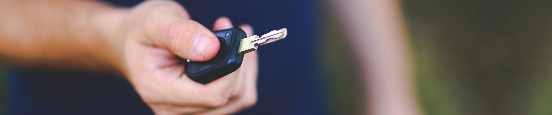Loan rates on used cars in Colorado Springs Phil Long Dealerships.png A man holding a set of car keys close up focus on his hand and car keys blurry background