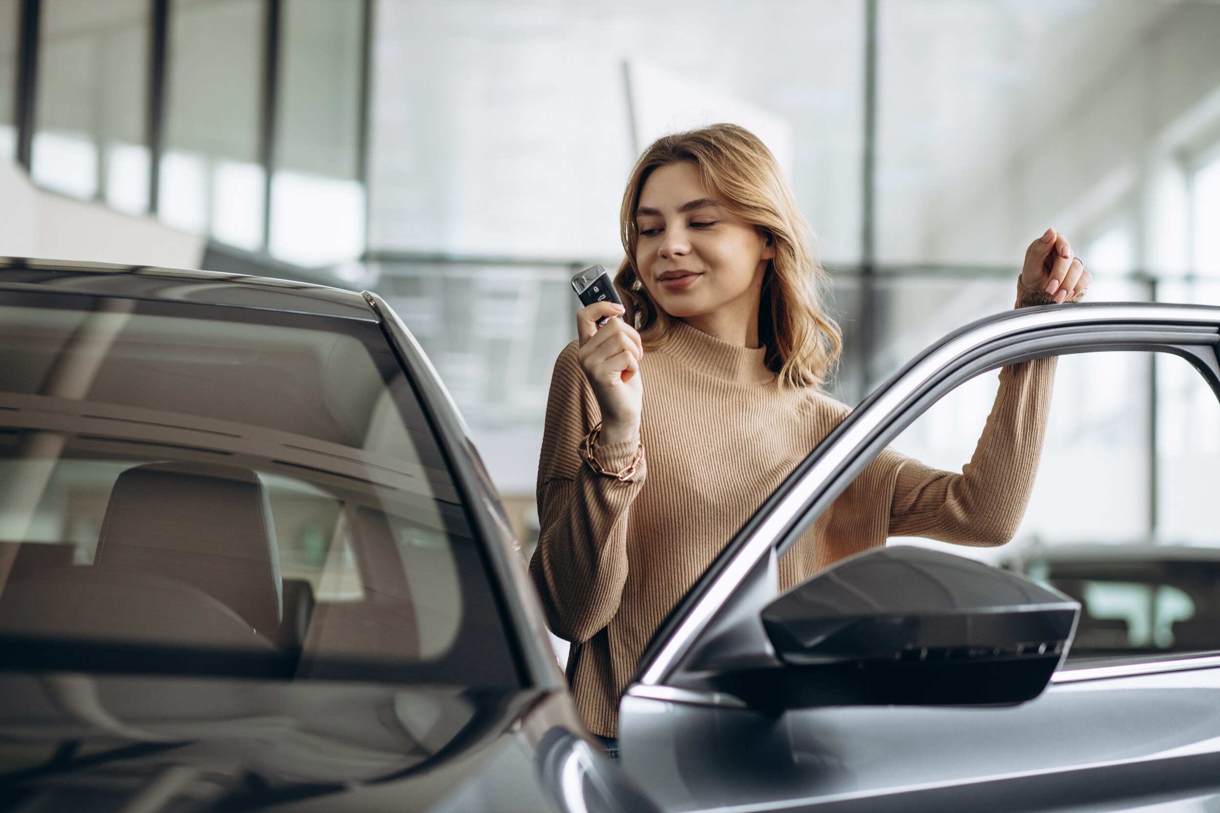 trading a car.jpeg A woman holds the key to her new car as she gets in the driver's seat
