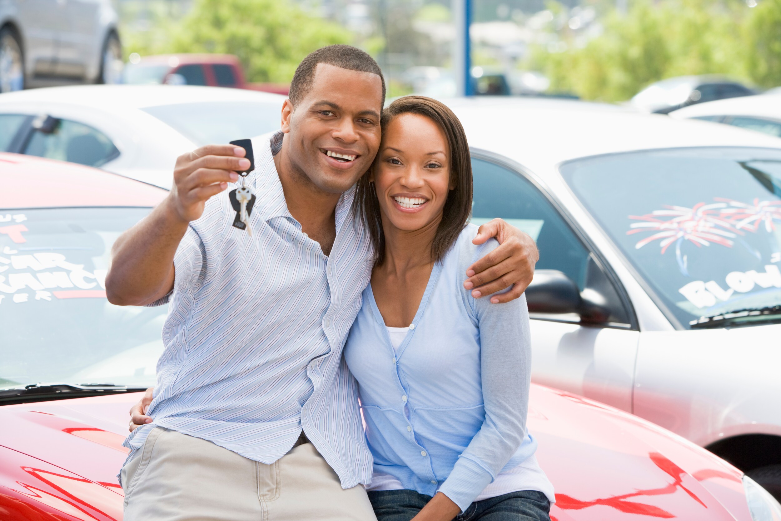 AdobeStock_7433492.jpeg A couple cuddles while the man holds the keys to a new car