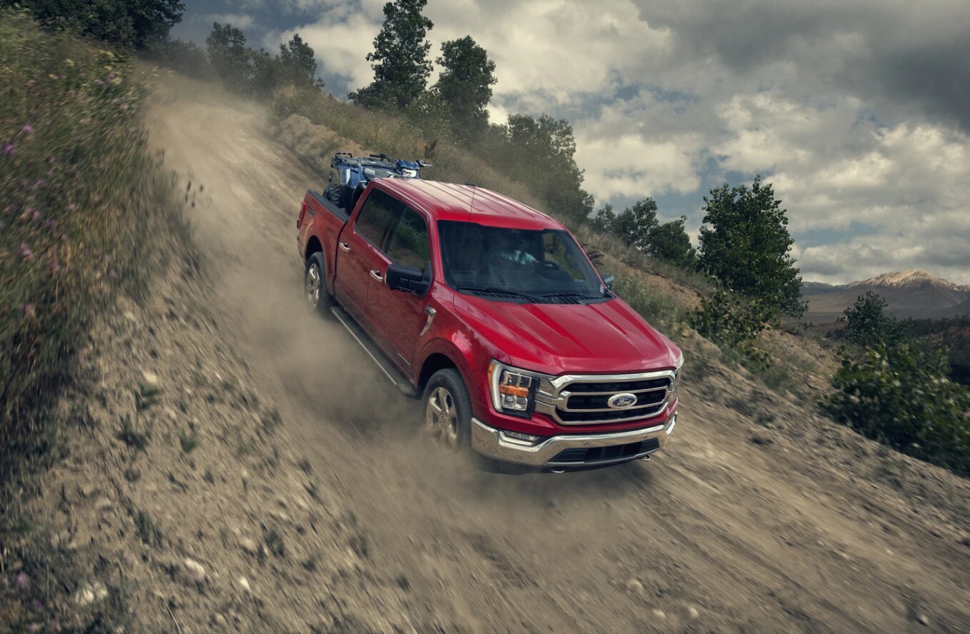 A new cherry red F150 speeds down a country road