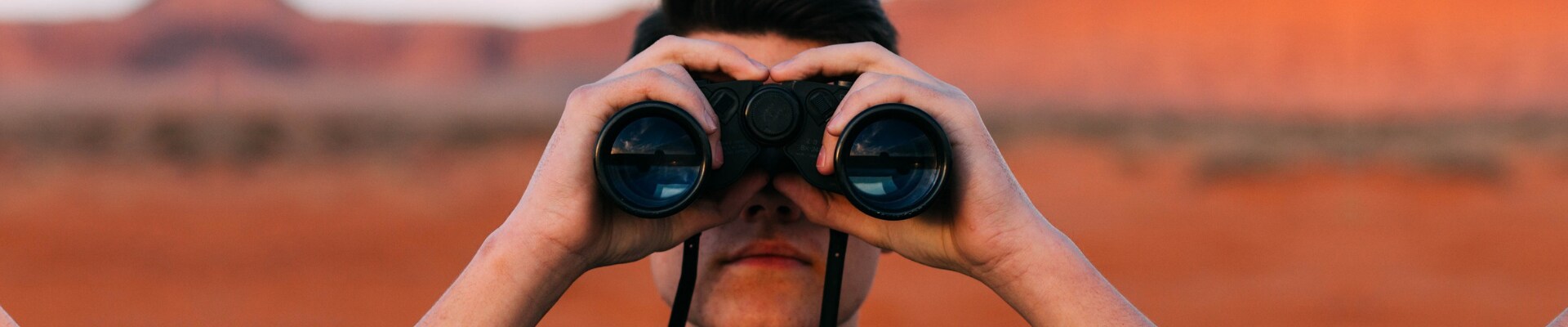 Where to find used cars in Colorado Springs at Phil Long Dealerships.png A young man looking through binoculars looking for places to buy used cars