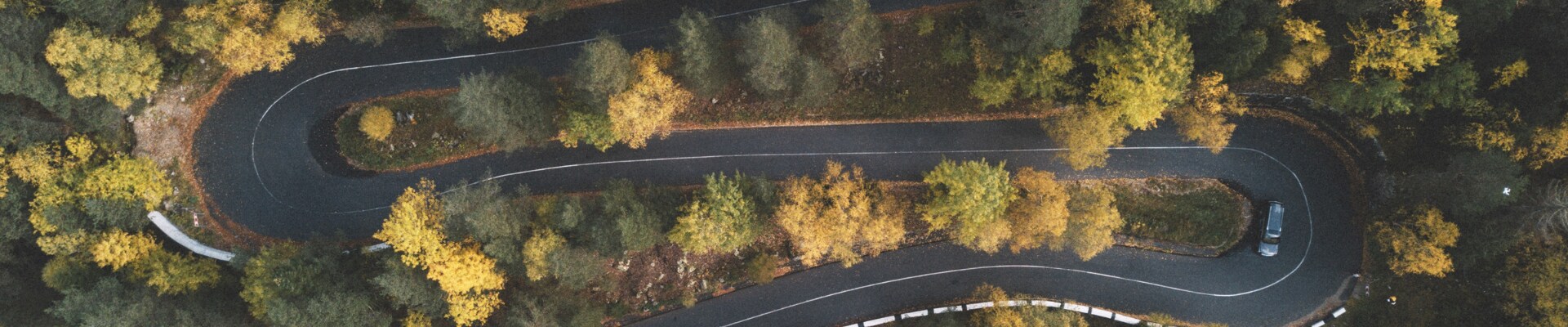 Used cars with best reliability in Colorado Phil Long Dealerships.png Aerial view of a used car as it drives down a winding curvy road through a forest