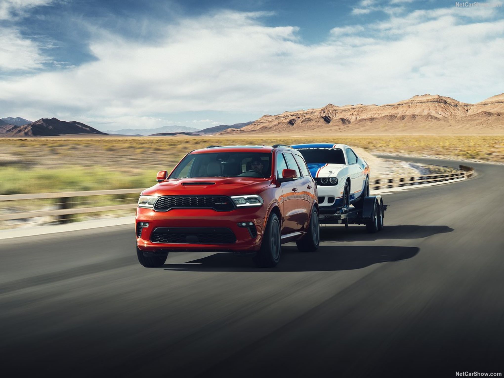 Dodge-Durango-2021-1280-0d.jpg A Dodge Durango driving while towing a classic sports car.